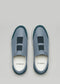 Top view of V27 Lake W/ Petrol Blue slip-on shoes with elastic bands on the upper, "D—VERGE" branding on insoles, set against a light gray backdrop. These handcrafted sneakers offer unmatched comfort and style, featuring ethically made elements and premium Italian leathers.