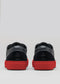 The V48 Deep Blue W/ Red sneakers feature black leather, black laces, and striking red soles, showcased from the rear against a simple gray background.