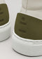 Close-up of the V52 Off-White W/ Olive sneakers, ethically handcrafted in Portugal. This pair features white with olive green heel accents, textured white soles, and minimalist geometric cut-out designs on premium Italian leathers.