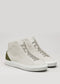 The V52 Off-White W/ Olive sneakers are high-tops made from premium Italian leathers, featuring a khaki green heel patch, minimalist design, and white rubber soles. Ethically produced in Portugal for the conscious fashion enthusiast.