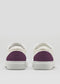 Against a gray background, the V52 Off White W/ Plum sneakers feature handcrafted white uppers with a striking plum heel detail, made from premium Italian leathers.