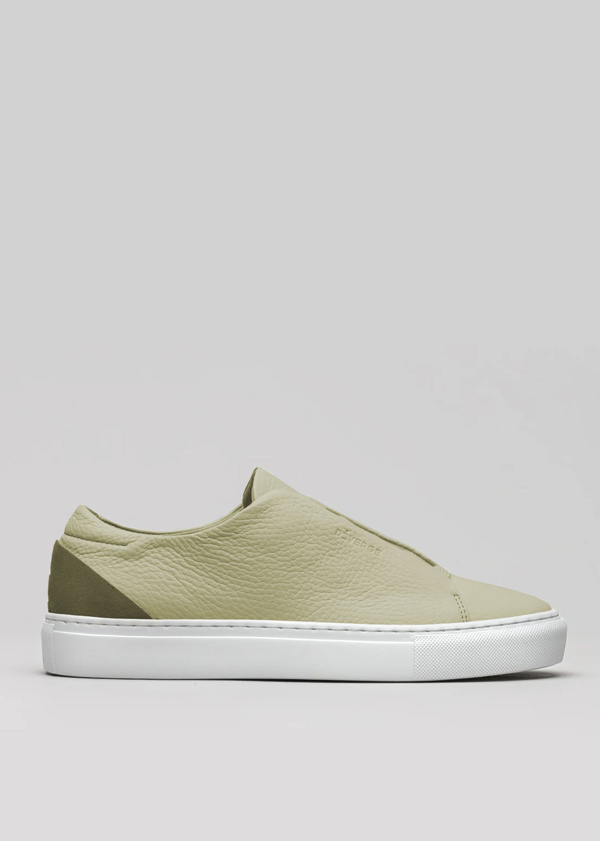 The V54 Sage Green W/ Olive sneaker, handcrafted in Portugal with premium Italian leathers, is showcased from the side. Its light green tones elegantly contrast with a white sole against a plain gray background.
