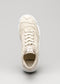 Una única zapatilla de lona V5 Full Color Antique White con el nombre de la marca "dé*verge" en la lengüeta, vista de frente sobre un fondo gris.