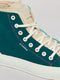 High-top sneaker with teal suede side, beige canvas upper, and white laces, featuring the brand name "DiVERGE X BUREL" in bold, silver text near the sole. These DiVERGE X BUREL Aqua & Teal high-top sneakers