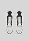 Top view of the V2 White & Black low-top sneakers, handcrafted in Portugal, featuring white laces on a gray background.