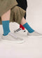 The two individuals strolling together include one wearing beige pants paired with blue socks and gray sneakers, while the other sports black pants accented by the V7 Brown & Caramel handcrafted, low-top white sneakers made from premium Italian leathers.