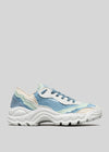 The LC0005 by Beatriz is a handcrafted sneaker with a white sole and a stylish layered design in blue, green, and beige fabric, set against a plain gray background.