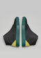 Une paire de chaussures compensées en cuir noir et vert MH0009 Jamaican Pride avec un design sculptural unique, présentées sur un fond neutre.