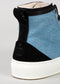 Vista ravvicinata di TH0005 by Mónica high-top sneakers con pannelli in denim blu e camoscio nero e suola in gomma bianca.