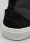 Nahaufnahme eines High-Top-Sneakers TH0007 Dark Fader mit strukturiertem Design, einer dicken weißen Sohle und einem Logodetail an der Ferse.