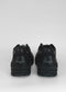 Un par de L0011 Black Leather low top sneakers con suela gruesa y las palabras "empowerment love" impresas en el talón, mostradas sobre un fondo gris.