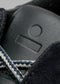 Nahaufnahme eines V7 Leather Color Mix Black Low-Top-Sneakers mit raffinierten Details wie einem strukturierten Muster, kontrastierenden weißen Schnürsenkeln und einer sichtbaren Größenangabe.
