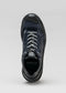 Una única zapatilla baja V7 Leather Color Mix Black con cordones blancos, vista desde arriba sobre un fondo gris claro.