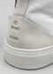 Primo piano di una sneaker high-top TH0004 by Martim che mostra la patch sul tallone testurizzata con logo in rilievo e la suola in gomma bianca.