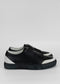 Un par de SO0010 Black & White lowtop slip-on sneakers con suela blanca, sobre un fondo gris neutro.