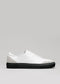 White slip-on sneaker with a black sole, displayed against a neutral grey background, SO0014 ALPINE NOIR.