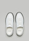 Un par de zapatos de piel SO0014 ALPINE NOIR con logotipo en la plantilla, sobre fondo gris.