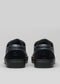 Vista trasera de un par de zapatillas V2 Blue Floater slip-on sneakers con suela de goma negra sobre fondo gris claro.