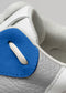 Primer plano de una zapatilla baja V18 Leather Color Mix Electric Blue blanca y azul que muestra detalles del tejido texturizado, las costuras y los cordones.