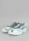 A pair of LC0004 Color Mix Jeans with blue, white, and yellow patches and white laces on a gray background.