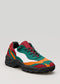 Una vibrante sneaker low top multicolore con pannelli verdi, arancioni, rossi e bianchi, caratterizzata da una robusta suola nera.