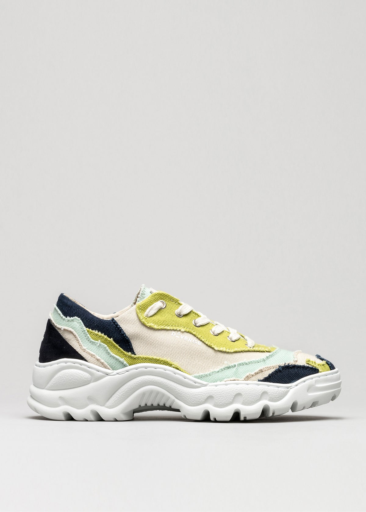 A multicolored low top sneaker with V2 Color Mix Sage Green patches on a light gray background.