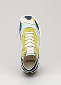 Vista frontale di una colorata sneaker low-top con patch V2 Color Mix Sage Green, lacci bianchi e marchio "d'verge" sulla linguetta.