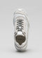Front view of a single V6 Leather Color Mix White sneaker with black laces and logo placement on the insole, against a gray background.