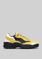 A yellow and black leather low top sneaker with a chunky black sole, displayed against a light grey background.