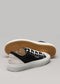 Un par de zapatillas V2 Full Color Black de lona sneakers con puntera blanca y suela de goma, sobre un fondo gris claro.
