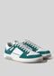 Une paire de baskets V1 Emerald Green W/ White sneakers avec des lacets blancs sur fond gris.