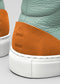 Close-up of the back heel of V38 Green W/ White leather high top sneakers with embossed "nike" logo on an orange suede patch and white soles.
