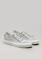 Un par de zapatillas de lona V3 Full Color Gris con cordones y suela blancos, sobre un fondo gris liso.