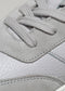 Nahaufnahme eines grauen Low-Top-Sneakers V2 mit detaillierter Ledertextur und Schnürsenkelmuster vor neutralem Hintergrund.