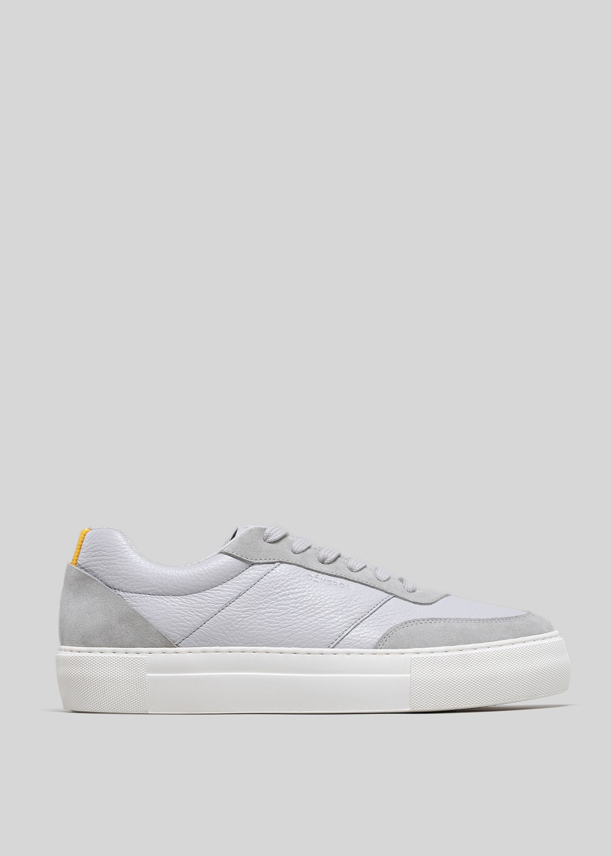 Side view of a V2 Grey low top sneaker with a white rubber sole and a small yellow tag on the heel.
