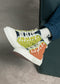 Une paire de TH0003 by Eduarda custom patchwork sneakers avec des lacets détachés, portée par une personne assise avec les chevilles croisées.