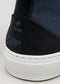 Primo piano di una sneaker V2 in tela blu marino e camoscio nero con suola in gomma bianca.