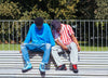 Two men sitting on a bench, wearing Diverge sneakers, promoting social impact and custom shoes throught the imagine project.