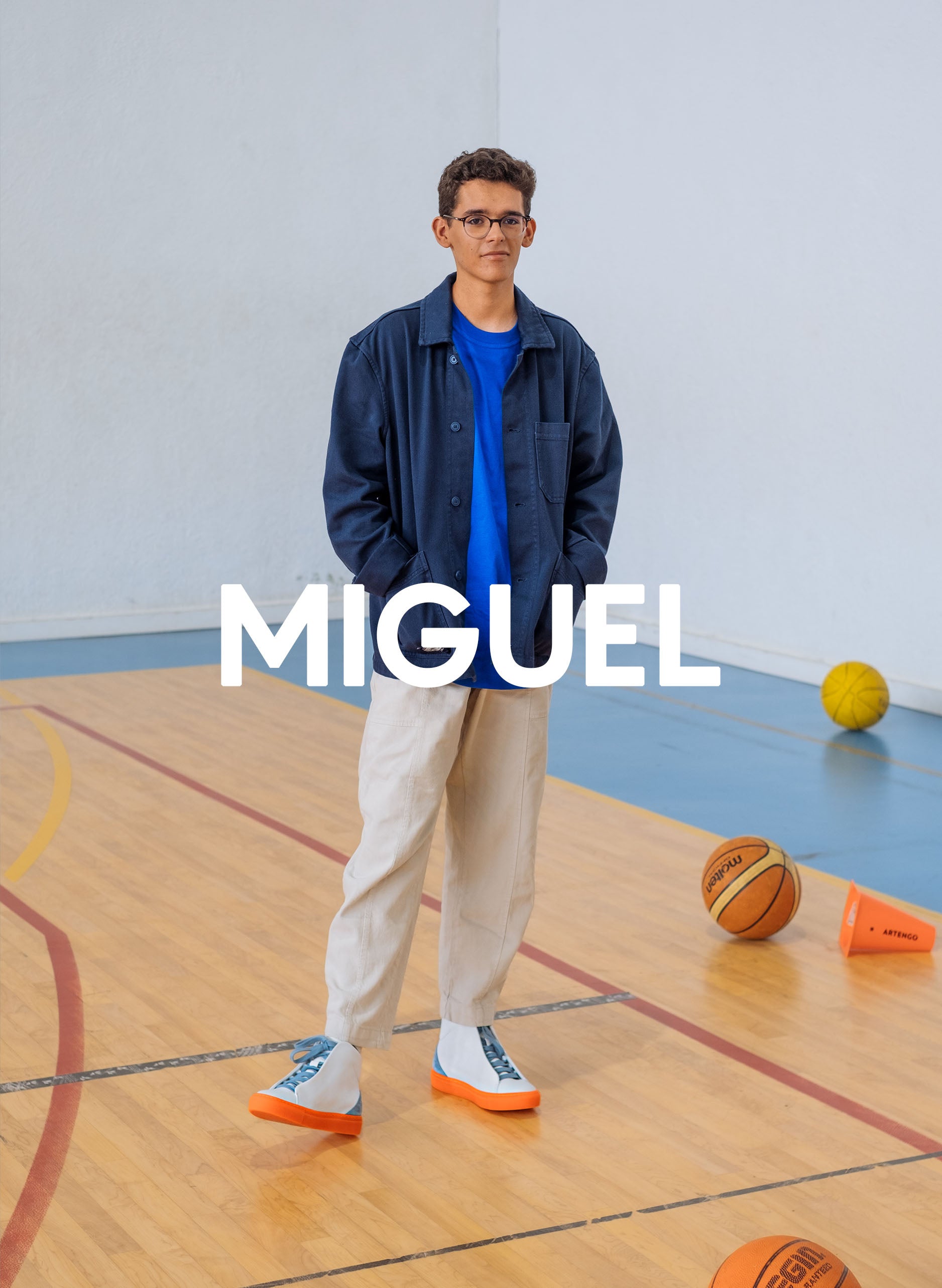 Miguel in a gym wearing a blue jacket, beige pants and also diverge sneakers, promoting social impact and custom shoes throught the imagine project.