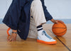 A man standing on the floor with a basketball, wearing Diverge sneakers, showcasing social impact and custom shoes throught the imagine project.