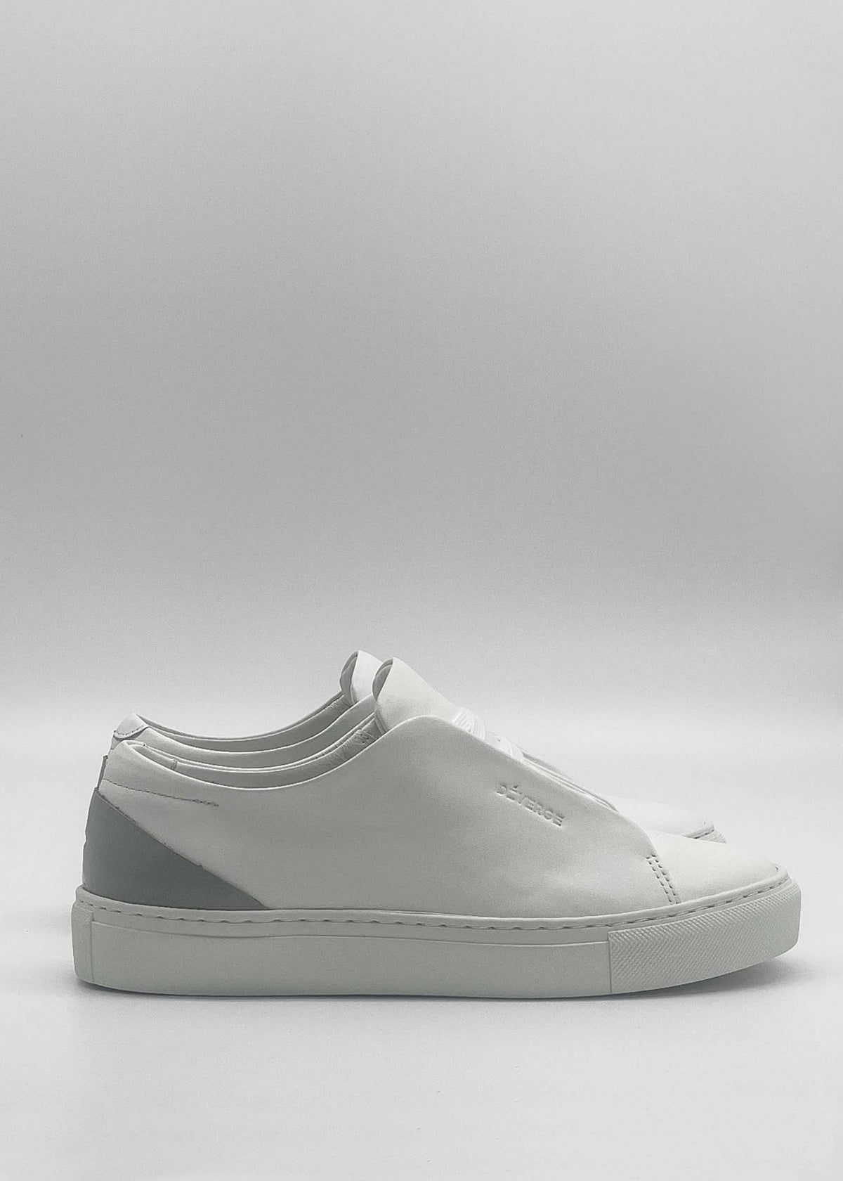 The ML0130 White W/ Grey are sleek, minimalist white sneakers handcrafted in Portugal from premium Italian leathers. They feature a smooth design with a light gray heel accent and white laces, displayed on a plain white background.