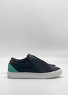 The ML0132 Black W/ Green sneakers feature a minimalist design with black leather, a teal detail on the heel, and a white sole. Handcrafted in Portugal with premium Italian leathers for exceptional quality and elegance.