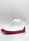 Discover the MH0154 White W/ Red sneakers, expertly handcrafted in Portugal with premium Italian leathers. These high-tops feature red soles and blue heel accents against a plain gray background.