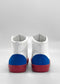 The MH0154 White W/ Red sneakers, handcrafted in Portugal, spotlight the elegance of premium Italian leathers with their white high-tops, blue heels, and red soles against a gray background.