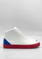 The MH0154 White W/ Red sneakers, handcrafted in Portugal, feature premium Italian leather, a blue heel accent, and a red sole. Displayed against a plain light gray background, they seamlessly combine style and quality.