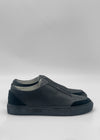 The SO0058 Black Leather is a pair of sleek, black slip-on sneakers made from premium Italian leather with a matte finish. These ethically crafted, minimalist shoes are showcased side view against a plain white background.