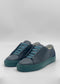 The ML0141 Black W/ Green sneakers are crafted from premium dark gray Italian leathers with teal soles and matching teal laces, handcrafted in Portugal, and showcased against a clean white backdrop.