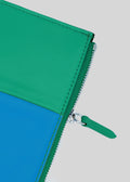 Primo piano di un M Patchwork Pouch Blue & Green con una cerniera verde parzialmente aperta, che rivela l'interno.