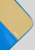 Vista en primer plano de una funda para ordenador portátil M Patchwork Pouch amarilla y azul con cremallera y el nombre de la marca "diverge" impreso en la parte amarilla.