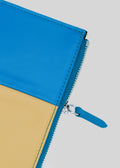 Nahaufnahme einer lebhaften M Patchwork Pouch Yellow & Blue Clutch Bag mit Reißverschluss und blauer Zuglasche auf weißem Hintergrund.